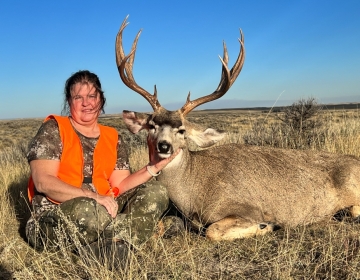 A female hunter poses with her 4x4 mule deer