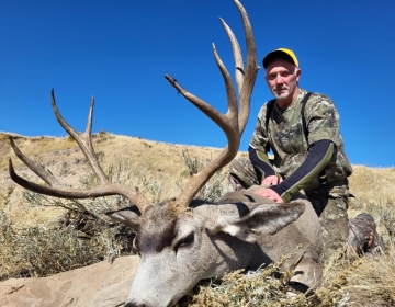 Wyoming hunter on a hillside with his mule deer trophy