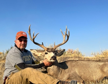 A hunter poses with a mule deer harvested during a successful hunt with SNS Outfitter & Guides in Wyoming.